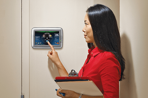 woman pointing to alarm system on wall