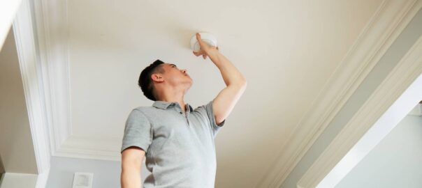 Man adjusting home carbon monoxide and fire detectors