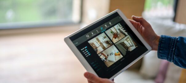 Woman monitoring her house with a home security system on her smart tablet