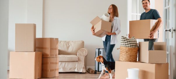 Young couple carrying cardboard moving boxes into new home