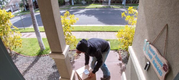 Package thief caught on video doorbell system stealing a box delivery from the front step of a suburban home